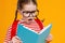 Astonished schoolgirl reading textbook during studies