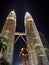Astonished traveler looking up to the illuminated Petronas twin towers in Kuala Lumpur