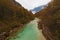 Astonishing landscape view of alpine Soca River. Emerald green water flows between mountains with dense forest.