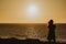 Astonishing sunset sky over the sea, and a girl standing and watching the calm surface, on a breeze