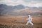 Astronaut explores an unknown red planet. Cloudy sky and mountains in the background