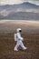 Astronaut explores an unknown red planet. Cloudy sky and mountains in the background