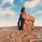 Astronaut sitting on a rock at a dry land .