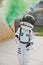 Astronaut in a space suit and a helmet holding a green smoke bomb