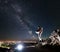 Astronaut standing on rocky mountain under fantastic starry sky.