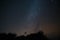 Astronomical telescope atop a hill, with the Milky Way galaxy illuminated in the background