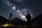 astrophotographer, with camera and tripod, capturing starry night sky above mountain range