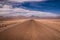 Atacama desert road during desert storm with Andes mountains in the background, San Pedro de Atacama, Chile