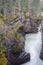 Athabasca Falls in the Rocky Mountains of Canada. Between the cliffs above the water stuck logs. Cloudy day in Jasper