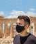 Athens Acropolis, Greece coronavirus days. Young man wearing protective face mask on Parthenon temple and blue sky background
