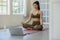 Athlete Asian indian woman looking laptop practice yoga lotus pose online course at home