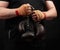 Athlete in a black uniform holds very old brown boxing gloves in his hand