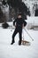 Athlete in black winter clothes pulls to the top of the slope a wooden sledge for a quick ride down and experience a piece of