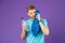 Athlete in blue tshirt and shorts with towel after training. Man hold water bottle on violet background. Sportsman with plastic bo