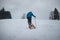 Athlete in blue winter clothes pulls to the top of the slope a wooden sled with accessories for photography and a plastic