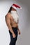 Athlete bodybuilder shirtless with long hair posing in cap Santa Claus