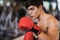 Athlete. Caucasian young man standing wear boxing glove color red and ready to fight on blurred background at the gym, fitness,
