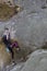 Athlete climbs on rock with rope.