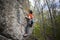 Athlete climbs on rock with rope.