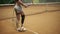 Athlete, disabled female collects tennis balls in the basket helping herself with a racket. Close up