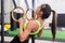 Athlete fit woman exercising in gym pulling up on gymnastic rings side view.