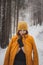 Athlete in fortuna gold winter jacket and yellow cap looking to the future. Girl with brown hair is covered by jacket. Portrait of