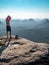 Athlete hiker takes off his sweaty shirt on top of the mountain