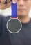 Athlete Holding Generic Gold Medal With Ribbon On His Hand.