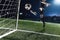 Athlete kicking soccer ball into a goal at night