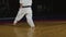 Athlete in kimono with does karate exercises in dark gym