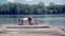 The athlete lies on the pier by the lake and is engaged in physical exercises.