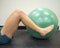 Athlete lying down with her legs around a fitness ball working out and doing exercises