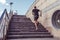 Athlete man runs in summer in city on steps, morning run, free space for text motivation fitness workout in fresh air