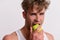 Athlete with messy hair eats fresh fruit. Man with apple