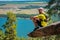 Athlete runner resting on the edge of a sticking cliff. View of the lake