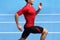 Athlete runner running on athletic track training cardio. Jogger man jogging fast pace for competition race on blue