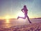 Athlete running on sandy seaside. Woman fitness sunrise or sunset jogging workout