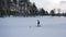 Athlete on a ski track near the forest and ski lodge in winter against grey evening sky. Footage. Sports and recreation