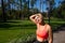 An athlete in sportswear does a neck stretch, helping herself with her hand and smiling. Outdoor sports