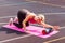Athlete sporty blond woman training on mat outdoor summer day, using foam roller massager for back pain