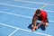 Athlete sprinter getting ready to run tying up shoe laces on stadium running tracks. Man runner preparing for race marathon