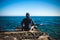 Athlete taking break sitting on rocks with sea horizon