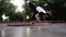 Athlete training parkour jump in city park. Acrobat practicing free running exercise. Man doing somersault and forward