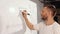 Athlete in white t shirt writes down exercises that he will perform on white board with a marker.