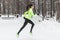 Athlete woman runner running in cold snowing weather. Cardio street training marathon jogging.