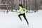 Athlete woman runner running in cold snowing weather. Cardio street training marathon jogging.