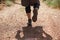 Athletes runner running down a mountain trail. A man runs through the mountains between the stones. View from behind. Man in