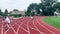 Athletes throwing medicine balls over track hurdles and squatting under to pick them up