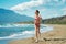 Athletic active runner woman jogging outdoors on beautiful tropical seashore with mountains view