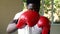 Athletic African American sportsman in red boxing gloves attacking during workout. Male boxer punching in gym